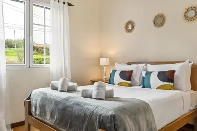 a bedroom with a large white bed with a window at Horizon Glow in Calheta