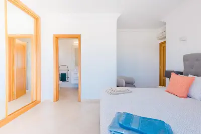 a white bedroom with a bed and a mirror at Casa Rosa1 at Boavista Resort in Lagos