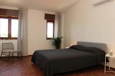 a bedroom with a bed and a chair and two windows at Casa Calma I in Luz