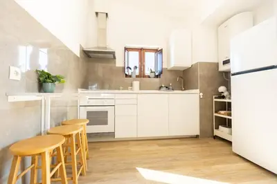 a kitchen with white cabinets and wooden stools at Casa Calma I in Luz