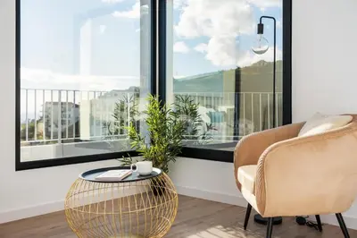 a living room with a chair and a table and a window at VIRA by KAAMAH in Estreito de Câmara de Lobos