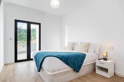 a white bedroom with a bed and a window at VIRA by KAAMAH in Estreito de Câmara de Lobos