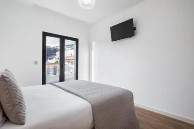 a white bedroom with a bed and a window at VIRA by KAAMAH in Estreito de Câmara de Lobos