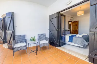 a bedroom with a bed and two chairs and a mirror at Spacious villa with sea view and heated pool - Luz - Casa Amizade in Luz