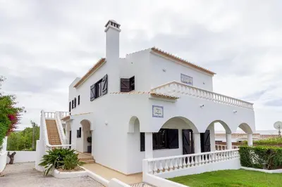 a white villa with a garden in front of it at Spacious villa with sea view and heated pool - Luz - Casa Amizade in Luz