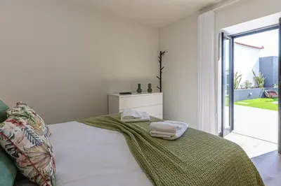 a white bedroom with a bed with two towels on it at Vila Sun House AB in Calheta