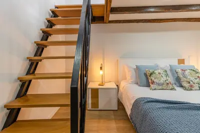 a bedroom with a bed and a spiral staircase at Vila Sun House AB in Calheta