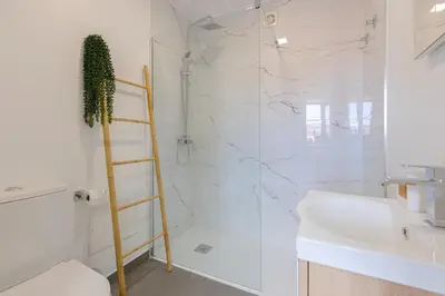 a bathroom with a shower with a ladder next to a sink at Vila Sun House A in Calheta
