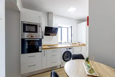 a kitchen with white cabinets and a table and a microwave at Vila Sun House A in Calheta