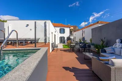 a backyard with a swimming pool and a house at Vila Sun House B in Calheta