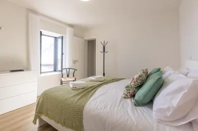 a white bedroom with a bed with pillows and a television at Vila Sun House B in Calheta