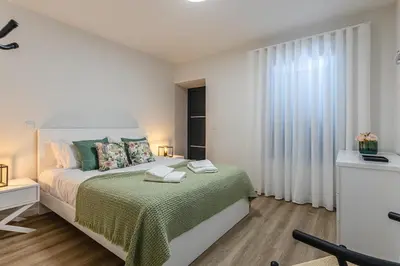 a white bedroom with a bed and a window at Vila Sun House B in Calheta