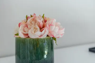 a green vase with pink flowers in it at Vila Sun House B in Calheta