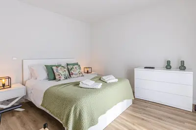 a white bedroom with a bed and a dresser at Vila Sun House B in Calheta
