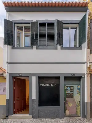 a white building with green shutters and a window at Studio 118 in Funchal