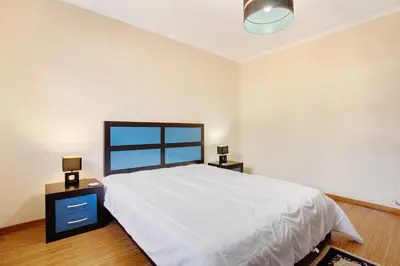 a bedroom with a large white bed and two night stands at Cristina Grand in São Vicente