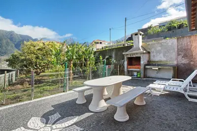 a table and two benches on a patio with a pizza oven at Cristina Grand in São Vicente