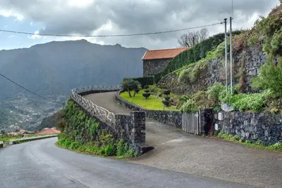 a stone wall next to a road on a mountain at Refugio Da Xamusca in São Vicente