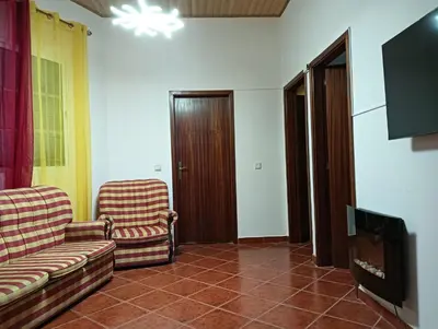 a living room with two chairs and a flat screen tv at Palm Comfort in São Vicente