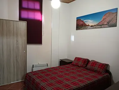 a bedroom with a bed with a red plaid blanket at Palm Comfort in São Vicente