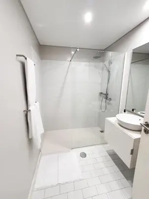 a white bathroom with a shower and a sink at Santa Luzia's Pearl I C - One Bedroom Apartment in Funchal