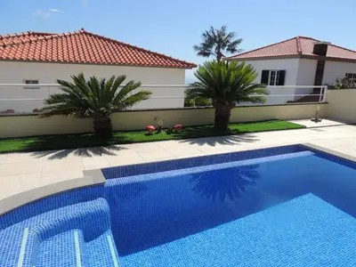 a swimming pool in front of a house with palm trees at Studio Flat with Pool in Funchal