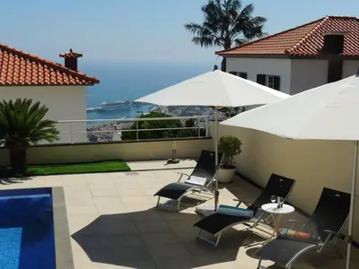 a patio with chairs and umbrellas and a pool at Studio Flat with Pool in Funchal