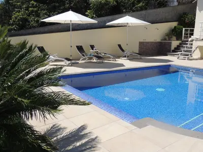 a pool with chairs and umbrellas and a palm tree at Studio Flat with Pool in Funchal