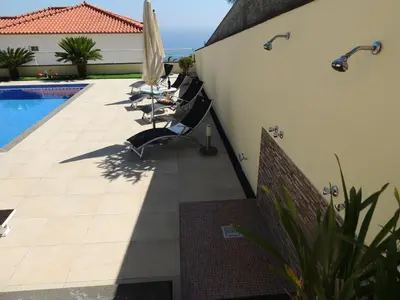 a patio with chairs and an umbrella next to a pool at Studio Flat with Pool in Funchal