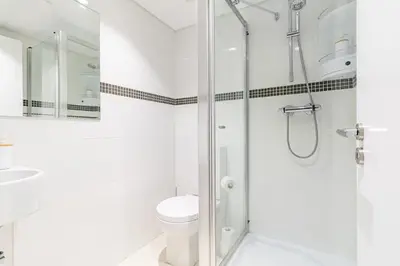 a white bathroom with a shower and a toilet at Sunset Cove in Funchal