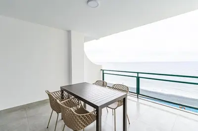 a dining room with a table and chairs and the ocean at Sunset Cove in Funchal