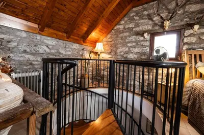 a spiral staircase in a room with a stone wall at Cabana da Quinta Girassol by YMR in Ponta do Sol