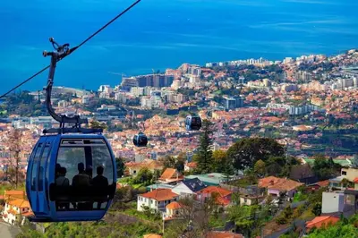 a group of people riding a gondola over a city at Center Marina view Gold Studio in Funchal