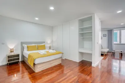 a white bedroom with a bed and a wooden floor at Mouraria Studios in Funchal