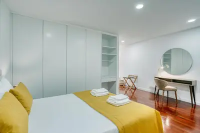a white bedroom with a bed and a desk at Mouraria Studios in Funchal