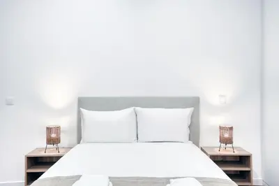 a bedroom with a white bed with two night stands at Mouraria Studios in Funchal