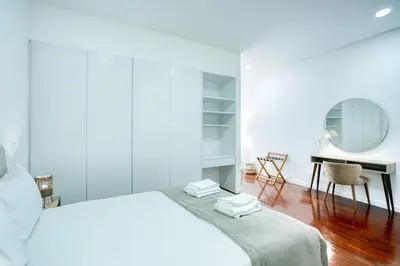 a white bedroom with a bed and a desk at Mouraria Studios in Funchal