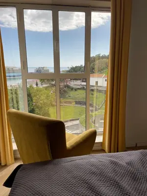 a bedroom with a large window with a chair in front at Center Marina view Yellow Studio in Funchal
