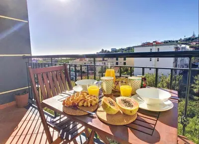 a table with breakfast foods and orange juice on a balcony at VeBella Abegoaria in Caniço