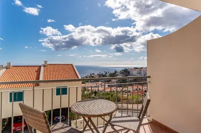 a balcony with chairs and a table and a view at Garajau View Apartment by Holiday Rental Madeira in Caniço