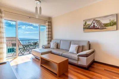 a living room with a couch and a large window at Garajau View Apartment by Holiday Rental Madeira in Caniço