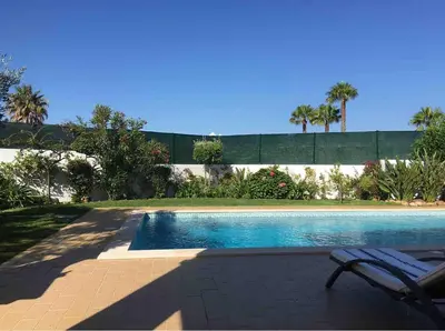 a swimming pool with a chair next to a fence at Praia da Luz Mandeliu Exclusive 5 Star Private Villa Heated Pool in Luz