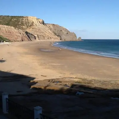 a beach with people walking on the sand and the ocean at Praia da Luz Mandeliu Exclusive 5 Star Private Villa Heated Pool in Luz