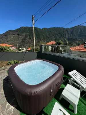 a hot tub on a patio with a chair and a table at Holiday home with game room and entertainment in São Vicente