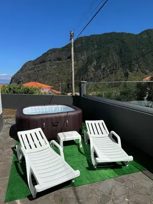 two white chairs and a hot tub on a patio at Holiday home with game room and entertainment in São Vicente
