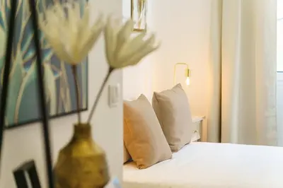 a bed with two pillows and a vase with a flower at GuestReady – Quaint Retreat in Funchal in Funchal