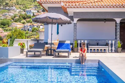 a woman sitting on the edge of a swimming pool at Casa dos Leões in Arco da Calheta