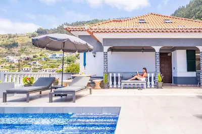 a woman sitting on a chair on the patio of a house at Casa dos Leões in Arco da Calheta