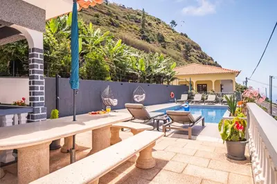a patio with a table and chairs next to a swimming pool at Casa dos Leões in Arco da Calheta