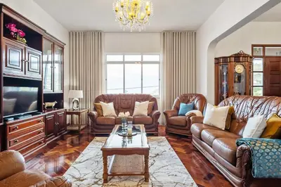 a living room with leather furniture and a chandelier at Casa dos Leões in Arco da Calheta
